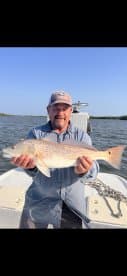 Angler proudly displaying a large Redfish while on a fishing trip in a coastal waterway.