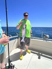 An angler proudly displaying a large fish aboard a boat in open waters, showcasing a successful fishing trip.