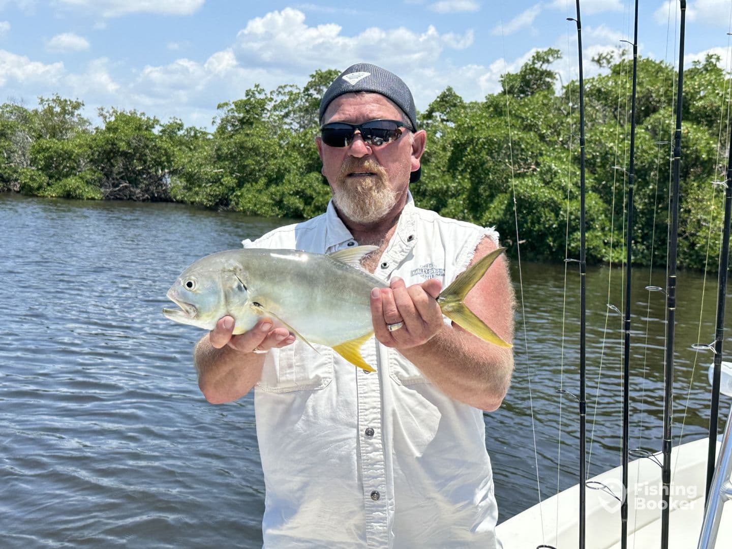 An angler proudly displaying a Silver Jack caught while fishing in a scenic mangrove area.