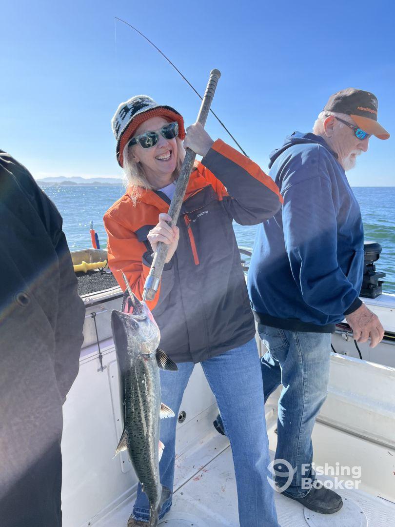 An enthusiastic angler reeling in a large fish while fishing on a boat, showcasing the excitement of the catch.