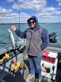 An angler proudly displaying a caught fish while aboard a fishing boat on a clear day, showcasing the excitement of a successful fishing trip.
