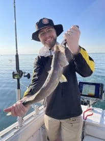 An angler proudly displaying a freshly caught Walleye while fishing on a sunny day, showcasing the excitement of a successful outing.