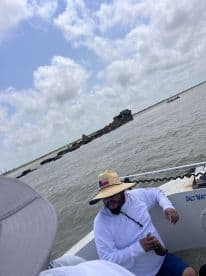 A relaxed angler seated inside a boat, enjoying the fishing experience with a scenic backdrop of an old structure in the water.