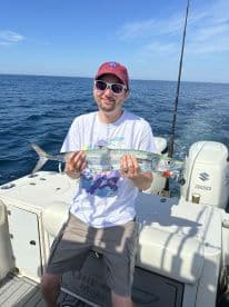 An angler proudly displaying a Barracuda caught during a deep-sea fishing trip on a sport fishing boat.