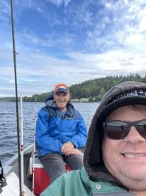 Two anglers enjoying a day on the water in a small boat, surrounded by scenic views of the lake and forest.