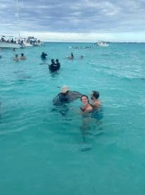 A lively scene in clear turquoise waters with several people enjoying a day out, possibly interacting with marine life.