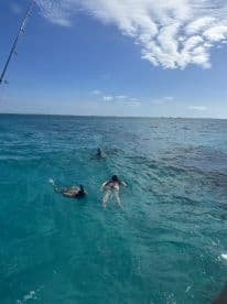 Group of individuals enjoying a swim in clear turquoise waters, likely during a fishing charter trip.
