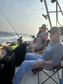 A family enjoying a fishing trip aboard a boat, with several members seated and relaxing while the boat navigates through the water.