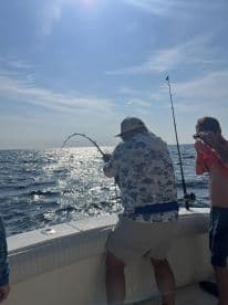 Angler actively reeling in a fish while enjoying a sunny day on the open water, showcasing the excitement of deep-sea fishing.
