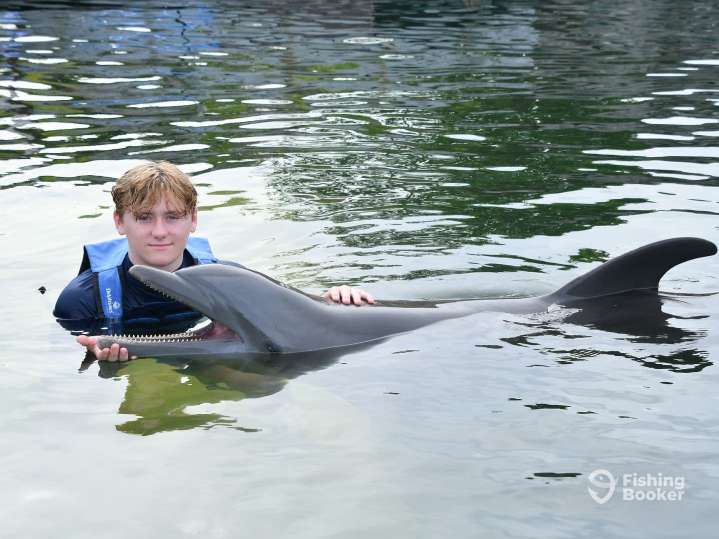 A young individual interacting with a dolphin in calm waters, showcasing a unique marine experience.