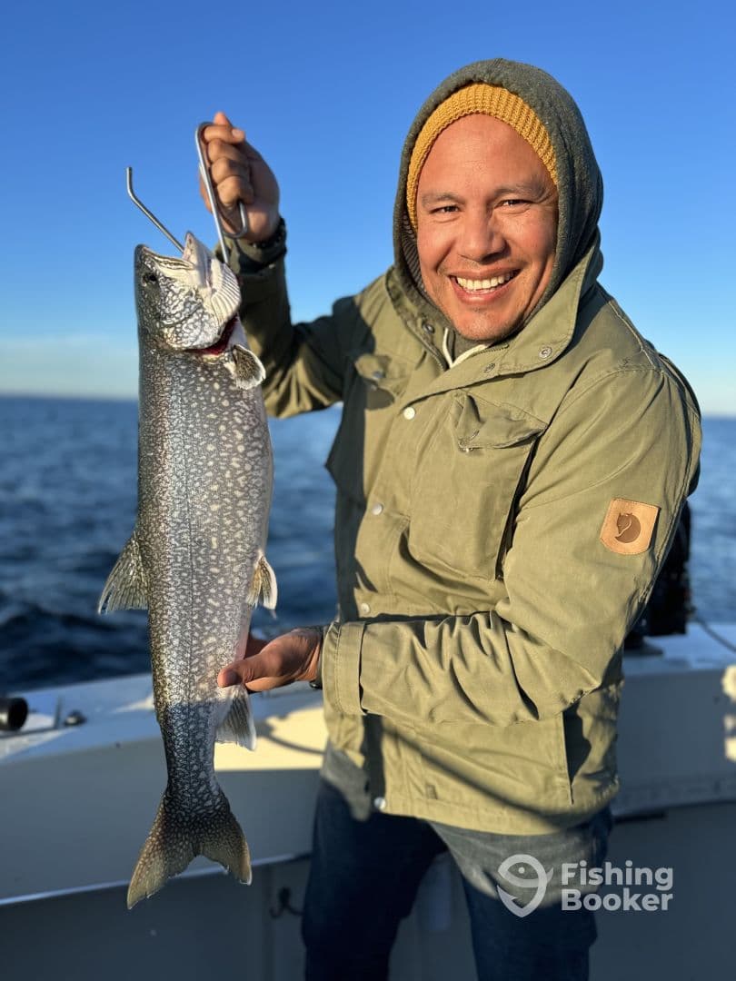 Angler proudly displaying a large Lake Trout while fishing on a clear day.