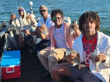 Group of anglers proudly displaying their catch of several fish while enjoying a day on the water.