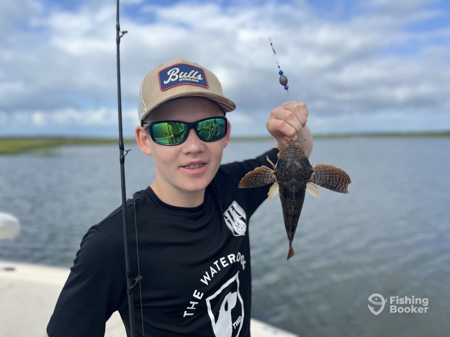 A young angler proudly displaying a caught fish while fishing in a scenic waterway, showcasing the excitement of a successful day on the water.