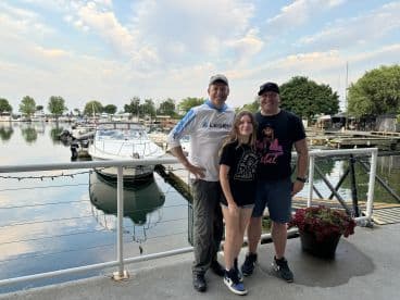 A family poses together at a marina, with boats visible in the background, capturing a moment of camaraderie before their fishing adventure.