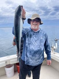 An angler proudly displaying a large fish while fishing on a boat, showcasing a successful day on the water.