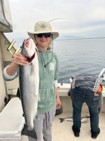 Young angler proudly displaying a large fish while fishing on a boat, showcasing a successful day on the water.