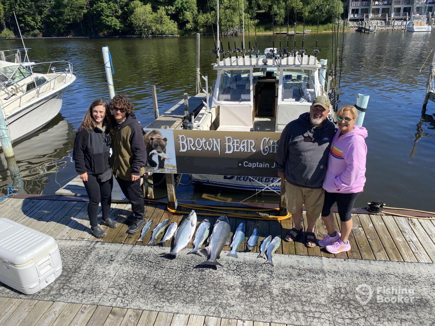 A group of anglers proudly displaying their catch of salmon on the dock after a successful fishing trip with Brown Bear Charters.