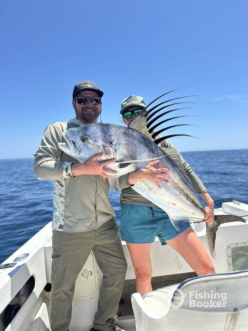 Two anglers proudly displaying a large Black Drum on a fishing boat, enjoying a sunny day on the water.