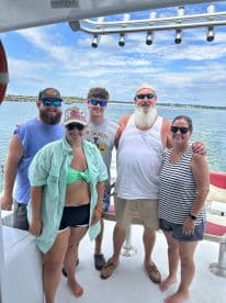 A group of five friends enjoying their time aboard a fishing charter, showcasing a relaxed atmosphere with scenic views of the water.