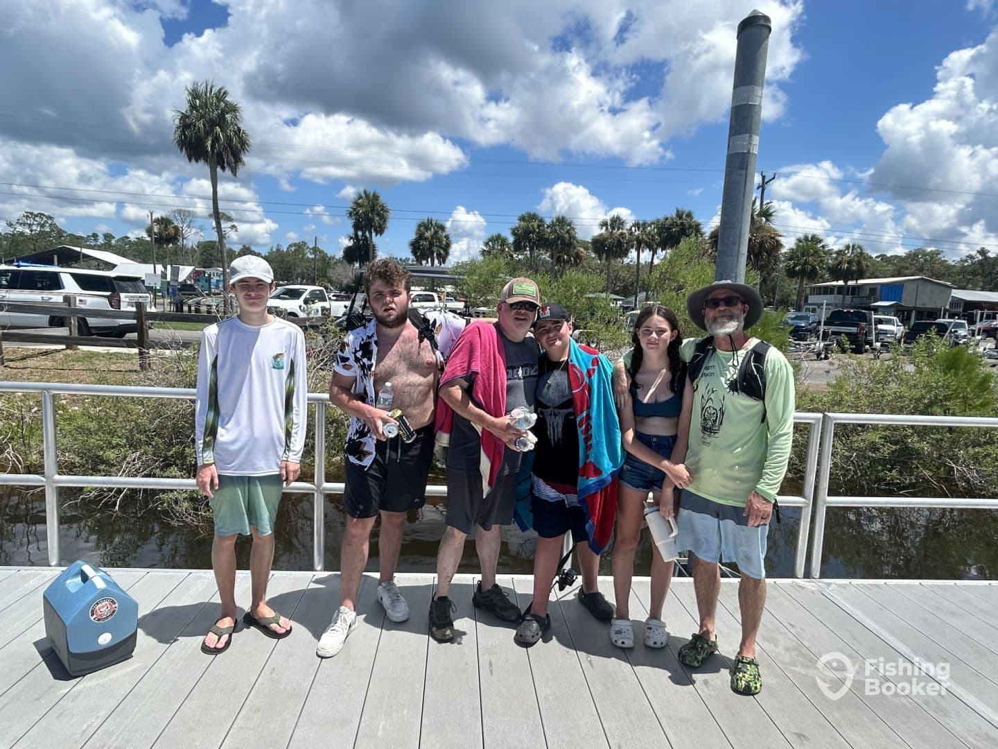A group of anglers posing together on the dock after a successful fishing trip, showcasing their catch in a vibrant outdoor setting.