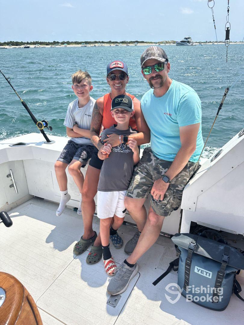 A family enjoying a day on the boat, with two kids and two adults posing together, showcasing a fun fishing experience.
