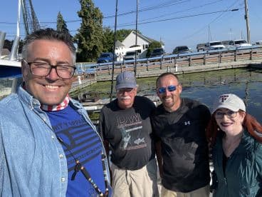 Group of four individuals posing together at a marina, likely preparing for a fishing trip.