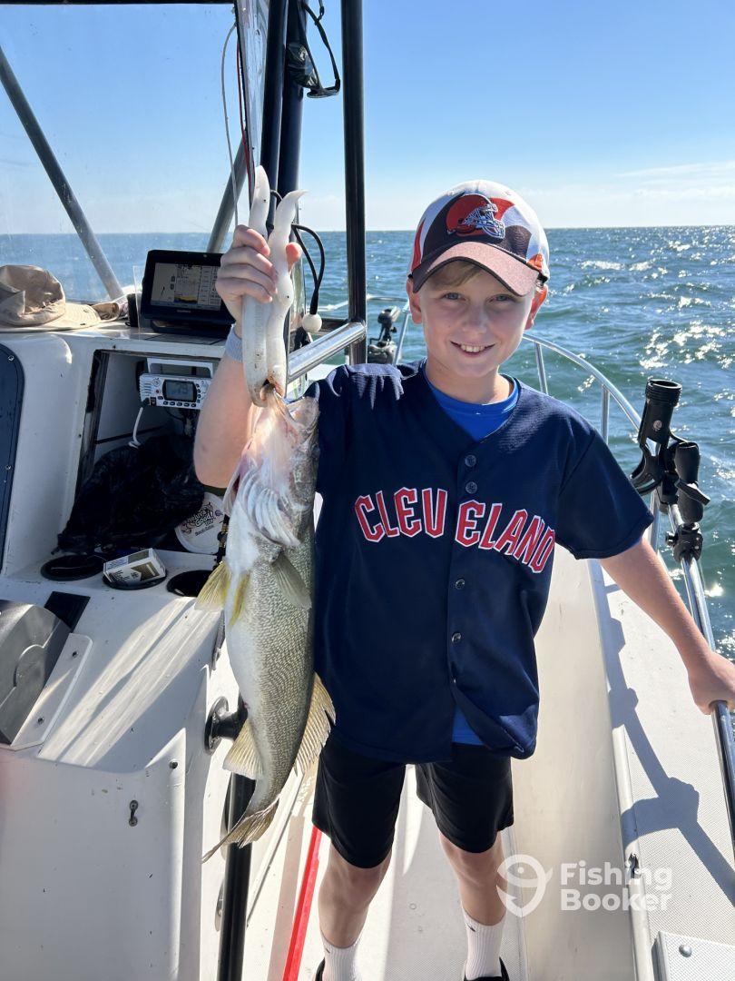 Young angler proudly holding a large Walleye while fishing on a boat, showcasing a successful day on the water.