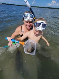 A mother and child enjoying a snorkeling adventure in shallow waters, exploring marine life with nets.