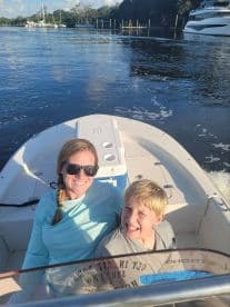 A mother and her son enjoying a sunny day on a small boat, showcasing a relaxed atmosphere on the water.