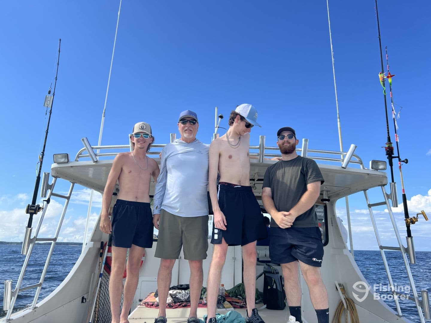 Group of four anglers enjoying a sunny day on a fishing boat, showcasing the boat's exterior and fishing environment.