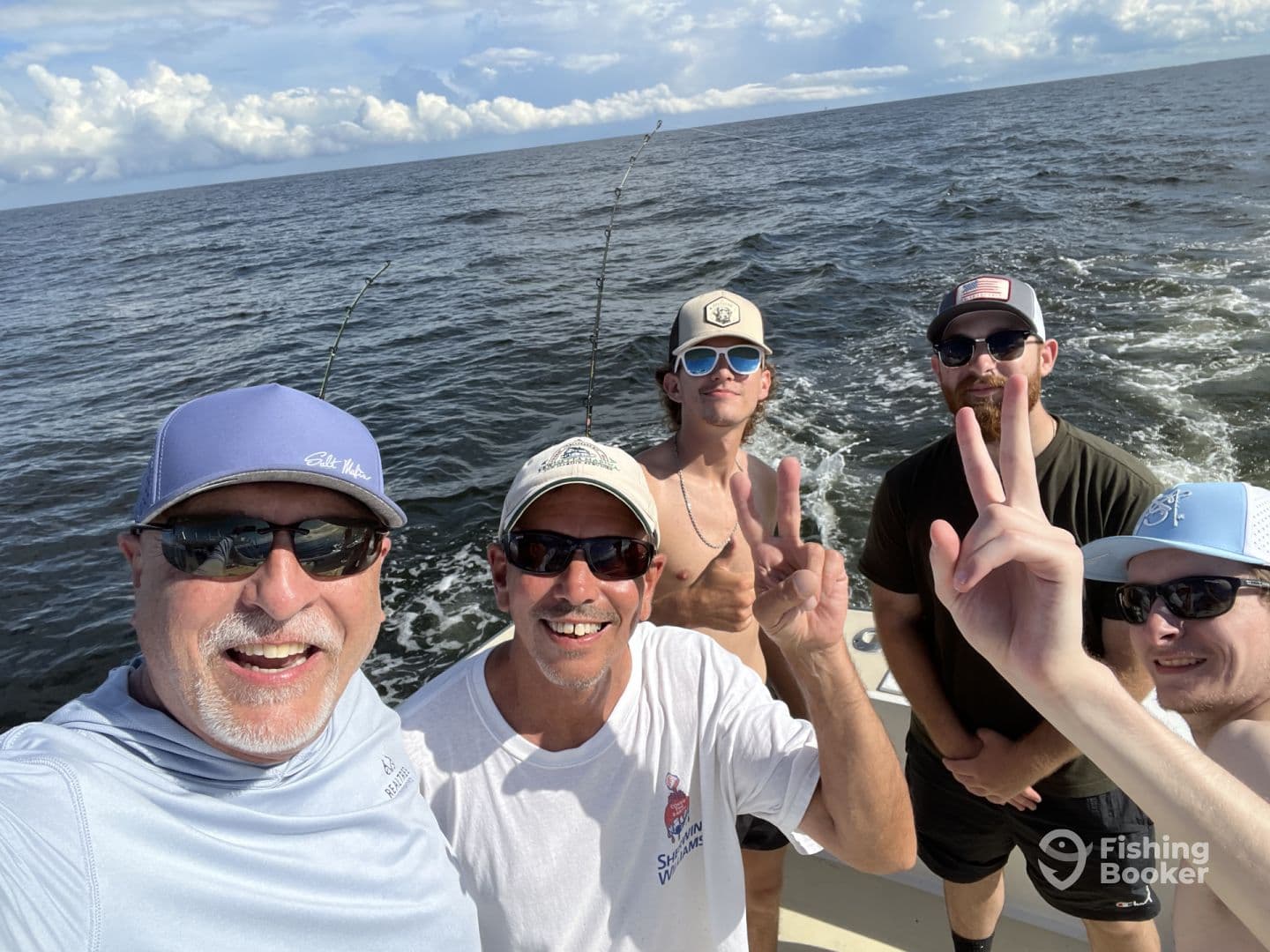 Group of anglers enjoying a day on the water, posing for a selfie on a fishing boat.