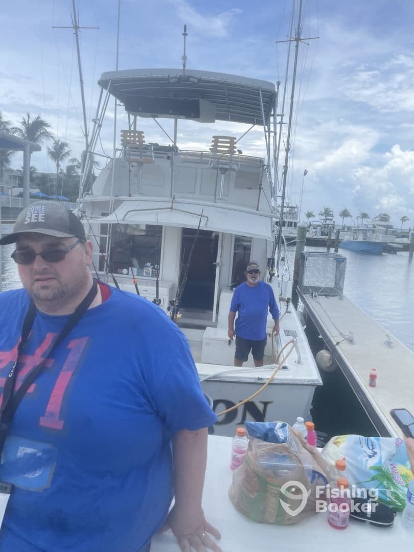 Two individuals are seen near the boat named 'ON', showcasing the vessel's exterior at a marina.
