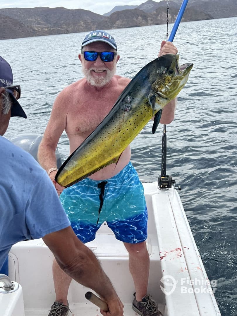 An angler proudly displaying a large Mahi Mahi while fishing in a scenic coastal environment.