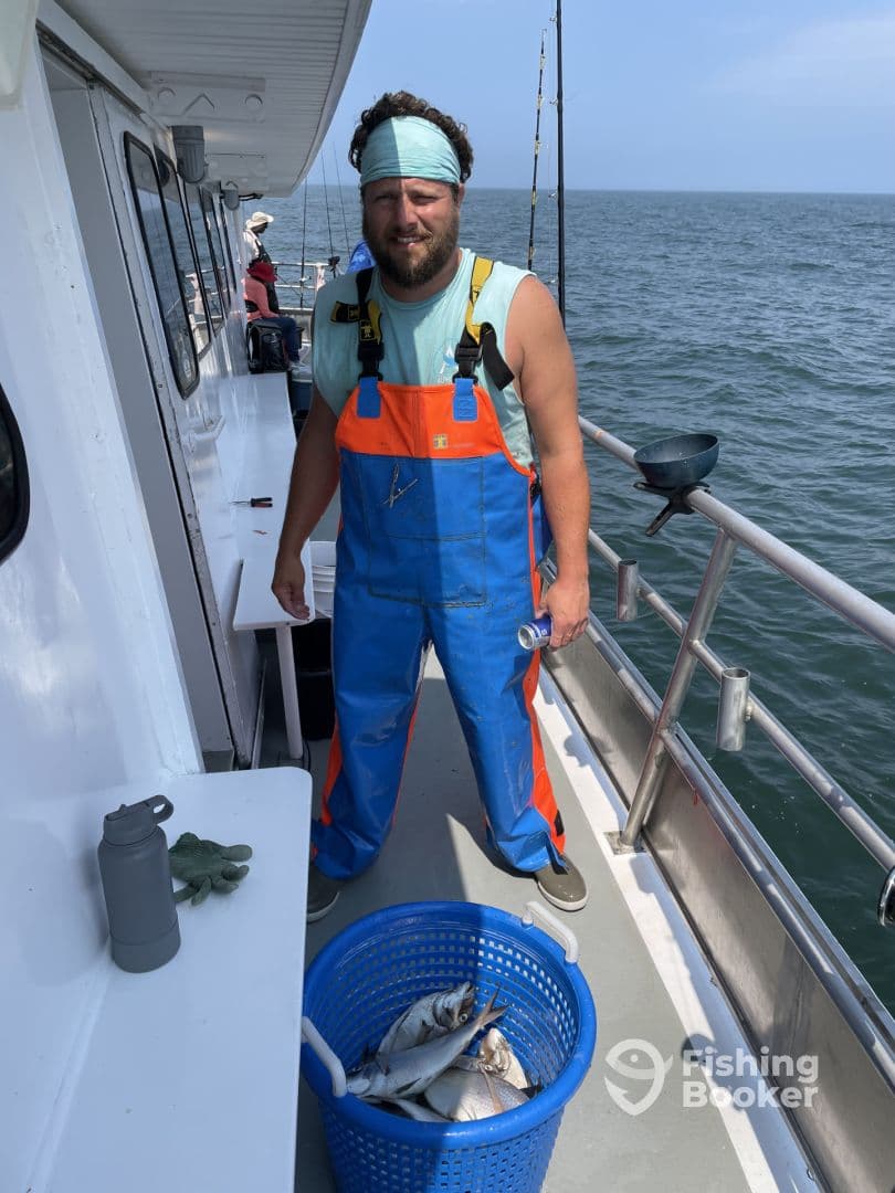 A fisherman on a charter boat displaying a blue basket filled with various fish, showcasing a successful day on the water.