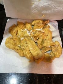 A plate of freshly fried fish fillets, likely from a recent fishing trip, displayed on paper towels.