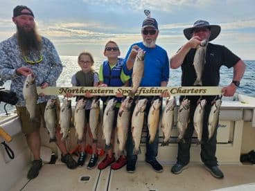 A group of anglers proudly displaying their catch of speckled trout on a fishing charter, showcasing a successful day on the water.