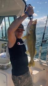 Young angler proudly holding a Walleye while fishing on a boat, showcasing a successful catch in a sunny environment.