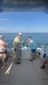 Two anglers proudly displaying their catch on a fishing charter in open waters, showcasing a sunny day and a relaxed atmosphere.