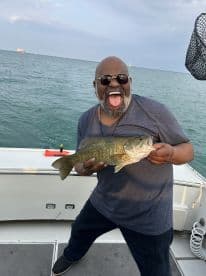 An enthusiastic angler proudly displaying a large Largemouth Bass while fishing on a boat, showcasing a vibrant fishing environment.