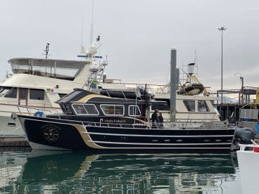 The 'Alaska Endeavor' is docked at the marina, showcasing its sleek design and spacious deck, ideal for fishing excursions.