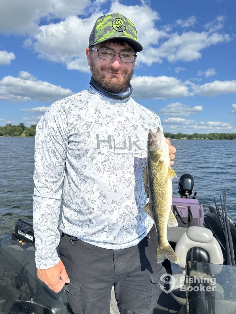 Angler proudly displaying a Walleye while fishing on a sunny day, showcasing a vibrant fishing environment.