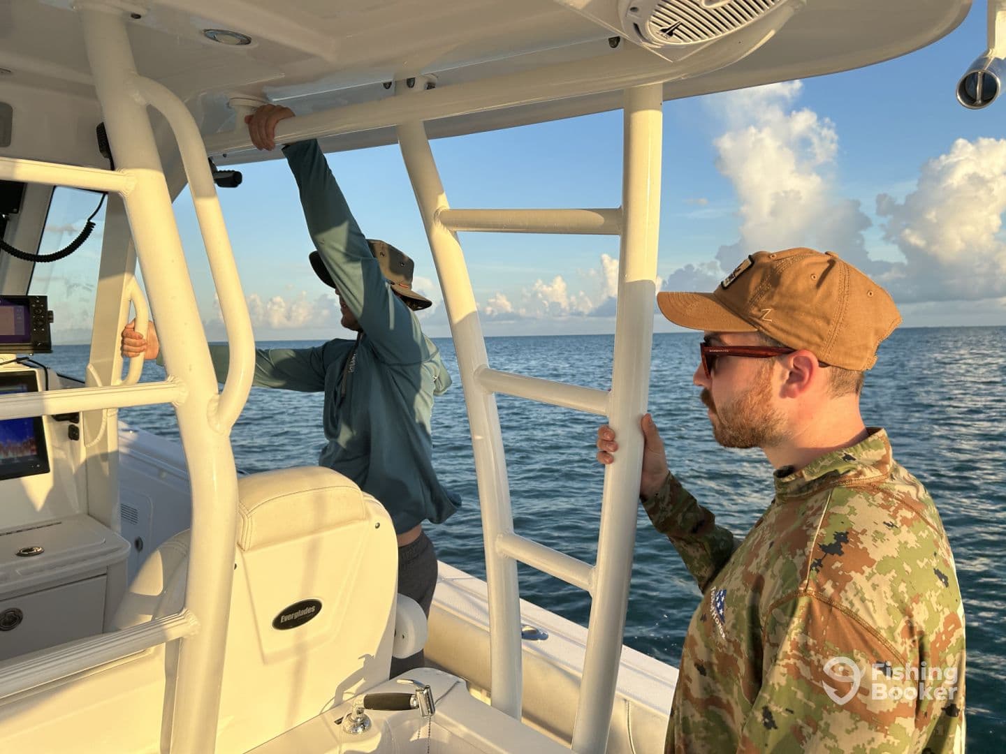 Two anglers inside a boat, one adjusting the helm while the other observes the serene ocean view, showcasing a relaxed fishing environment.