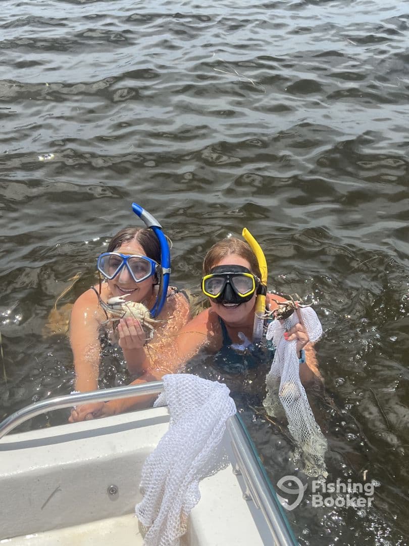 Two young snorkelers proudly displaying their catch of crabs while enjoying a fun day in the water.
