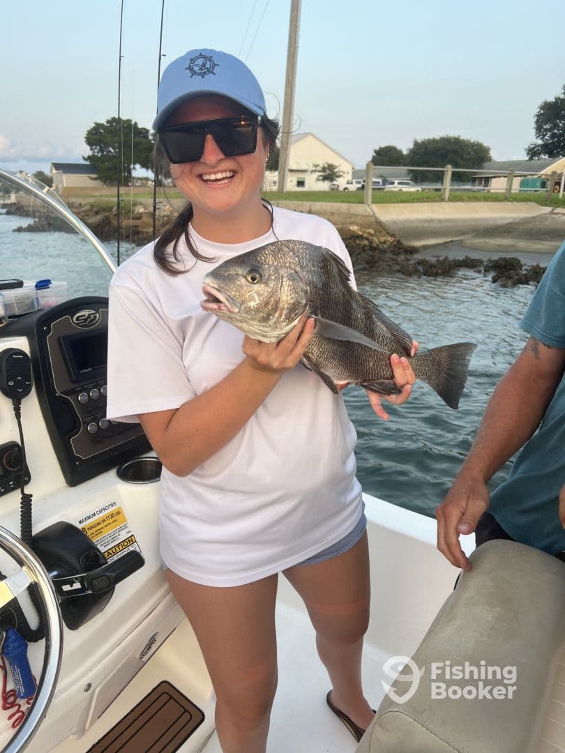 An angler proudly displaying a large Black Drum caught while fishing from a boat, showcasing a fun day on the water.