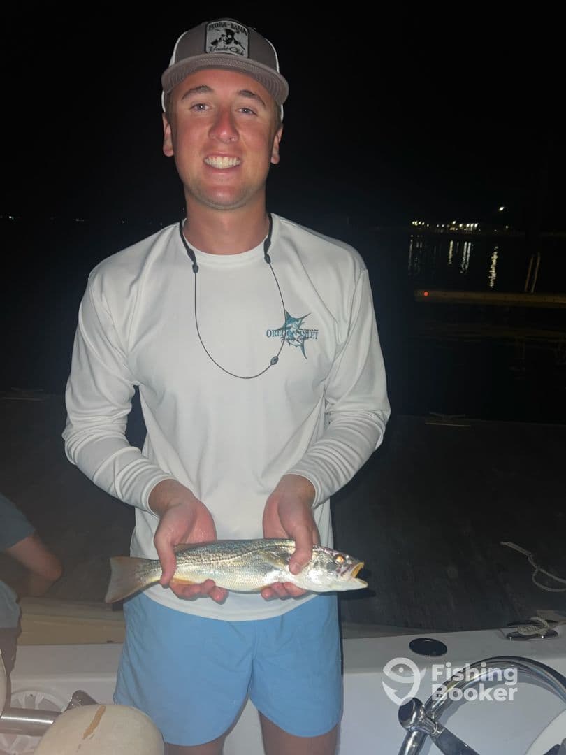 A young angler proudly displaying a Speckled Trout caught during a night fishing trip.