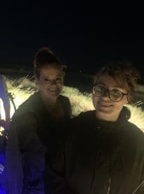 Two smiling individuals posing together at night, likely enjoying a fishing trip.