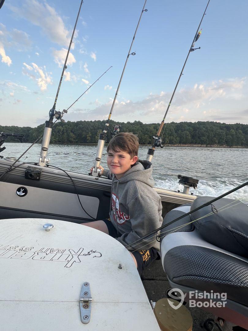 A young angler seated inside a fishing boat, enjoying a day on the water with fishing rods ready for action.