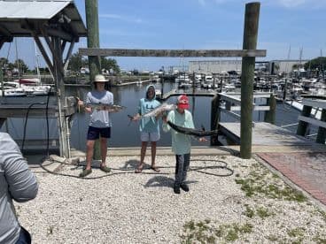 A group of young anglers proudly displaying their catch, including a large Barracuda and Kingfish, at Amelia Island Marina.