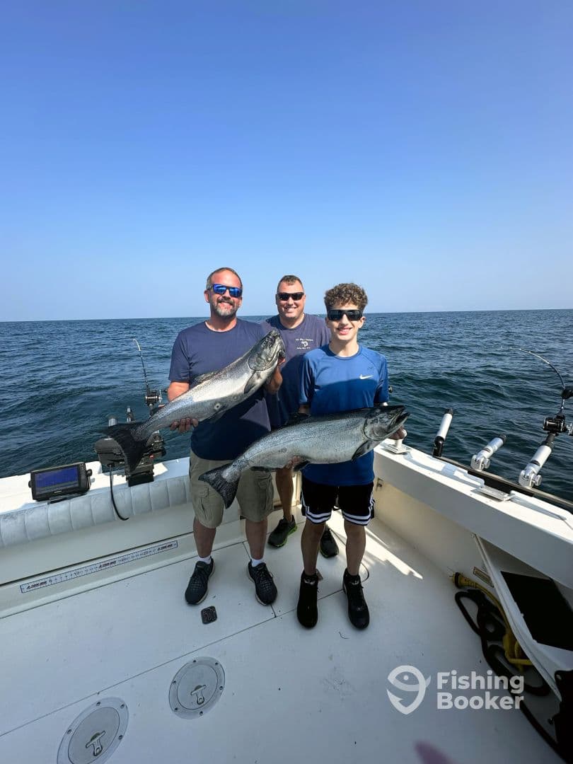 A family group proudly displaying their catch of two large Salmon while on a fishing trip in open waters.
