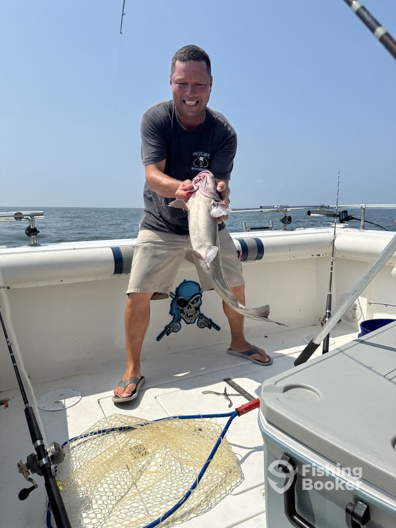 An angler proudly displaying a large catfish aboard a fishing boat, enjoying a sunny day on the water.